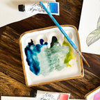 Another overhead view of "The Kris Palette". The palette is shown with cool-toned paints in use.