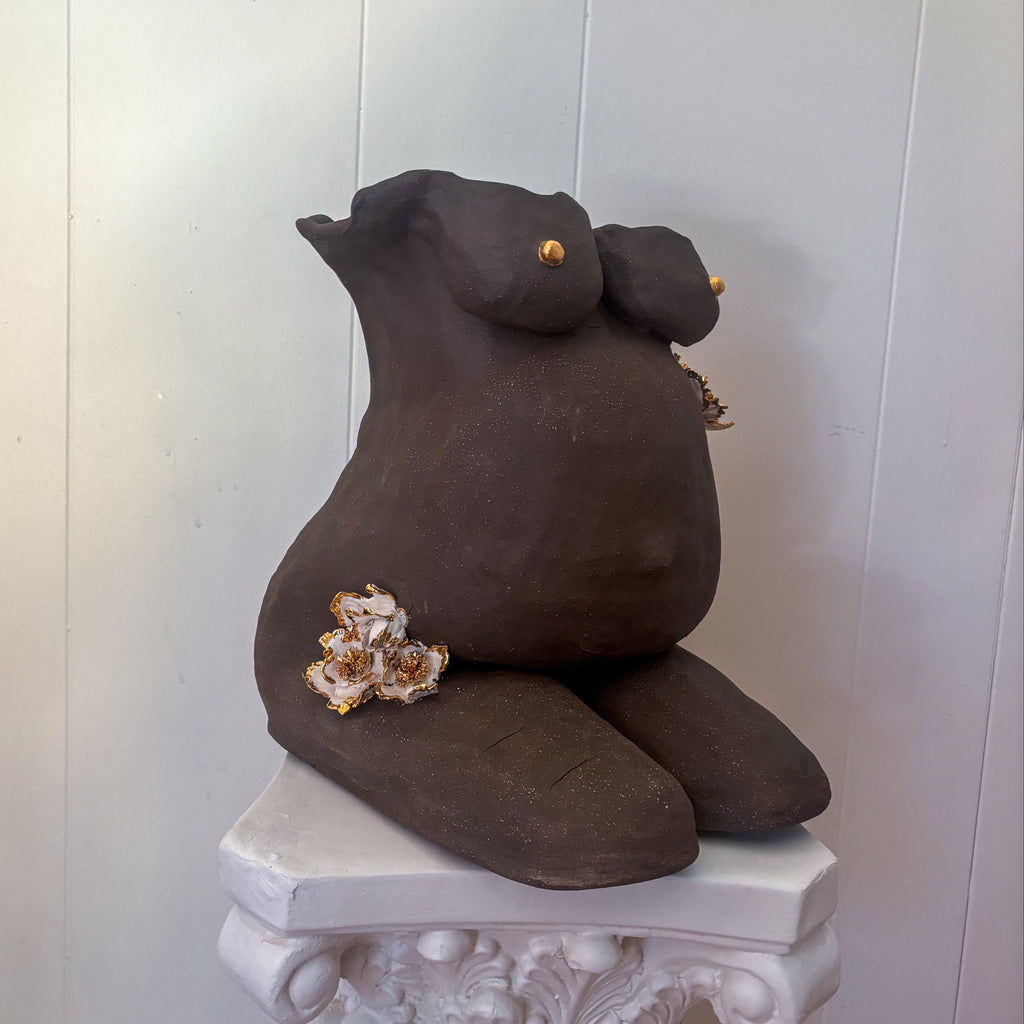 A 45º-angle view featuring the right side of the sculpture "She Who Carries".