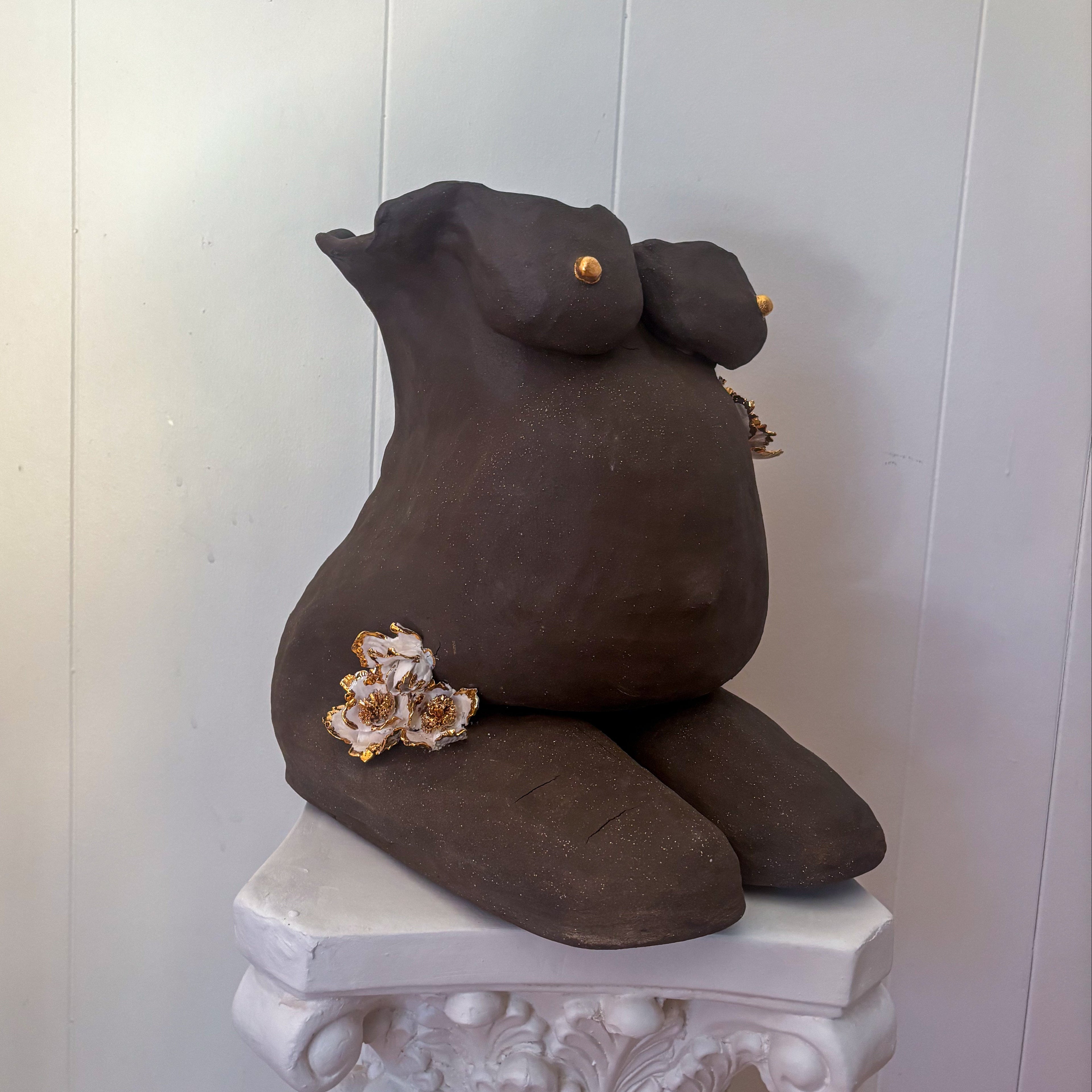 A 45º-angle view featuring the right side of the sculpture "She Who Carries".