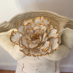 A close-up view of the 22k gold trimmed floral detail of the sculpture "She Who Holds".