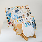A side angle view of a bamboo palette rack displayed with 4 painters palettes.