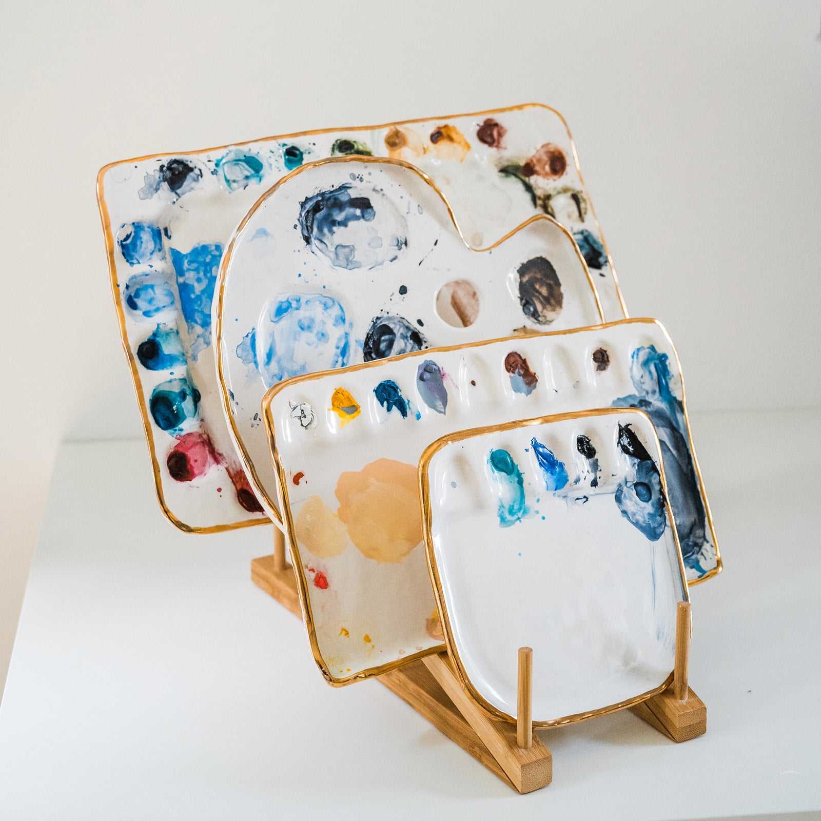 A side angle view of a bamboo palette rack displayed with 4 painters palettes.