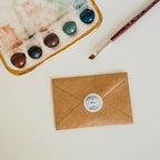 An overhead view of a brown paper envelope sealed with Eleni's sticker seal.