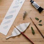 An overhead view of "The Imogene Brush Rest" an elegant, leaf-shaped rest, handcrafted from locally sourced porcelain and finished with a 22k gold edge.